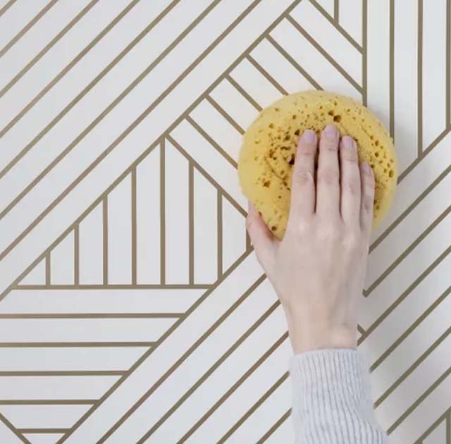a-hand-cleaning-geometric-bathroom-wallpaper-with-a-sponge-highlighting-the-wallpaper-s-easy-to-maintain-surface A hand cleaning geometric Bathroom Wallpaper with a sponge, highlighting the wallpaper's easy-to-maintain surface.