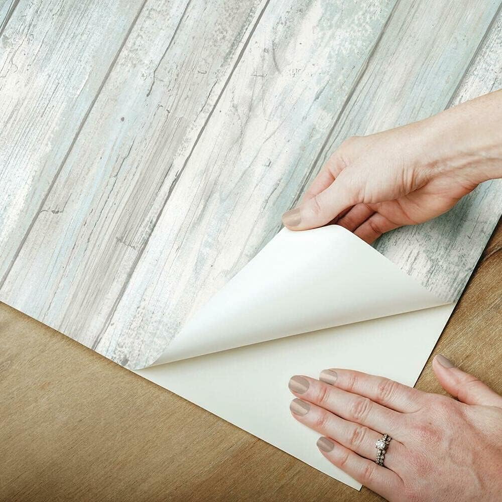 hands-peeling-off-the-backing-of-wood-textured-bathroom-wallpaper-preparing-it-for-application-on-a-surface Hands peeling off the backing of wood-textured Bathroom Wallpaper, preparing it for application on a surface.