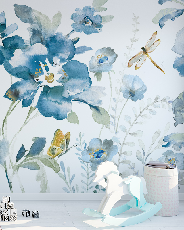 A nursery room with large blue floral wallpaper, highlighting blue wallpaper trends, features a dragonfly, butterfly, wooden rocking horse, and a storage basket