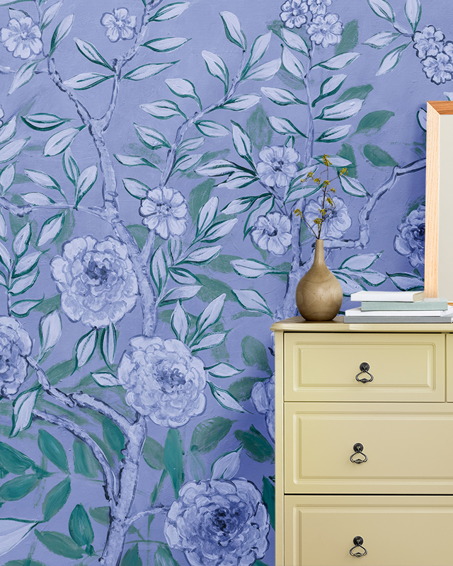 A room featuring blue floral wallpaper with green leaves, highlighting blue wallpaper trends, and a beige cabinet with a vase