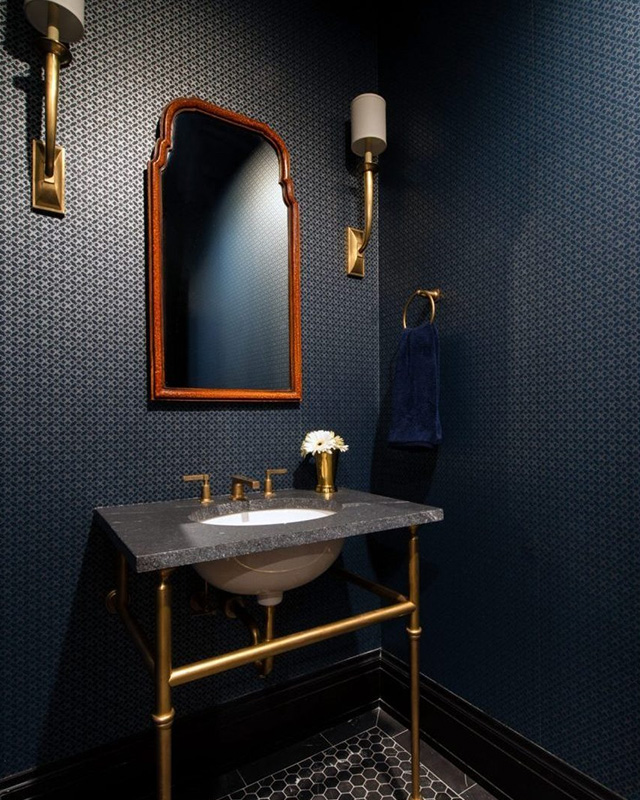 elegant-bathroom-with-dark-blue-wallpaper-and-lighting-from-gold-wall-sconces-featuring-a-black-countertop-and-gold-fixtures elegant bathroom with dark blue wallpaper and lighting from gold wall sconces featuring a black countertop and gold fixtures