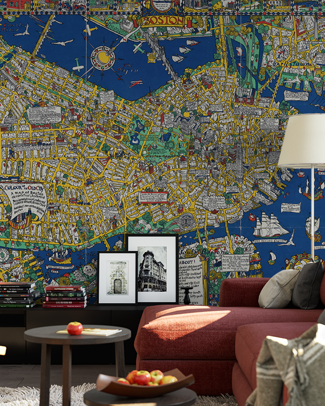 Living room with blue wallpaper trends featuring a colorful map of Boston, a red sofa, a floor lamp, framed pictures, and a coffee table with apples