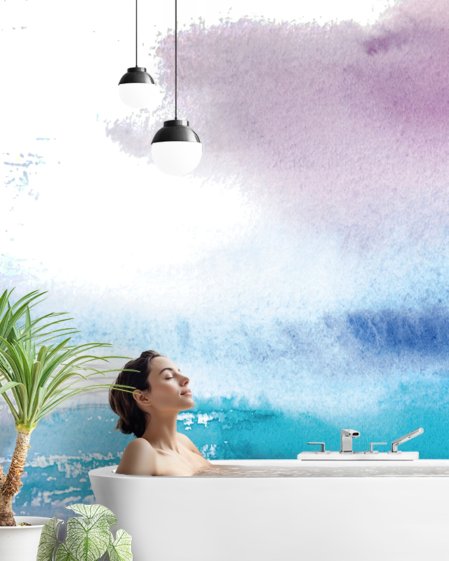 woman relaxing in bathtub against gradient blue wallpaper trends with modern pendant lighting and green plant nearby