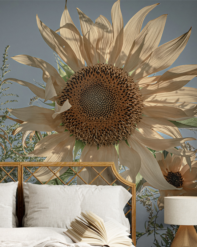 Floral Wallpaper Trend featuring a large, detailed sunflower design. In front of the wallpaper, a wooden bed frame with neutral pillows and an open book Floral Wallpaper Trend featuring a large, detailed sunflower design. In front of the wallpaper, a wooden bed frame with neutral pillows and an open book.