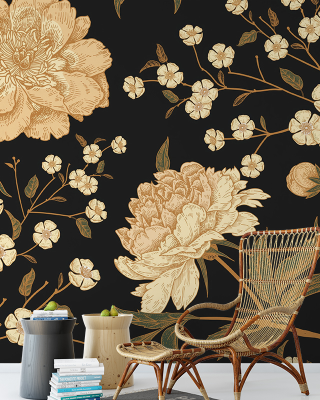 Floral Wallpaper Trend featuring large beige flowers and delicate blossoms on a black background. In front of the wallpaper is a wicker chair, a side table, and a stack of books. Floral Wallpaper Trend featuring large beige flowers and delicate blossoms on a black background. In front of the wallpaper is a wicker chair, a side table, and a stack of books.