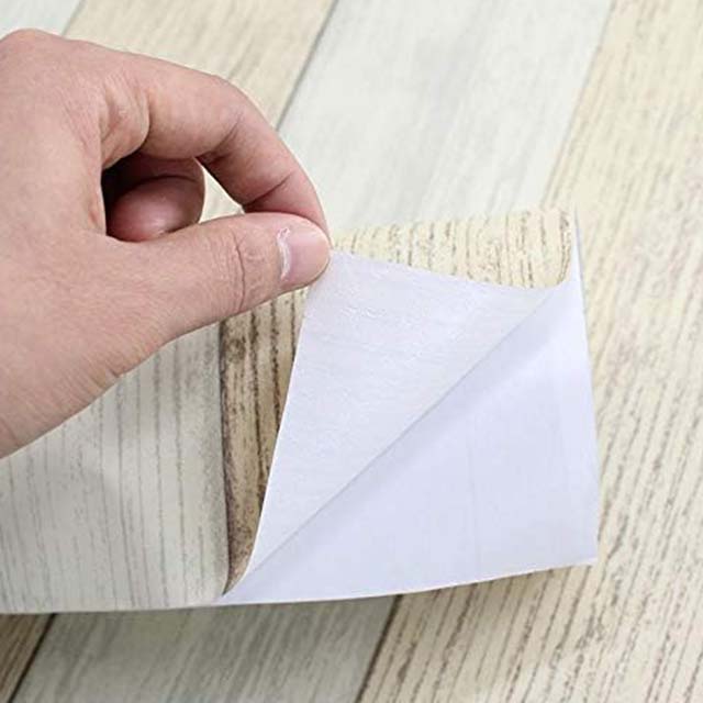 Hand-peeling-off-the-backing-of-a-wallpaper-sheet-during-the-Wallpaper-Installation-process. Hand peeling off the backing of a wallpaper sheet during the Wallpaper Installation process.