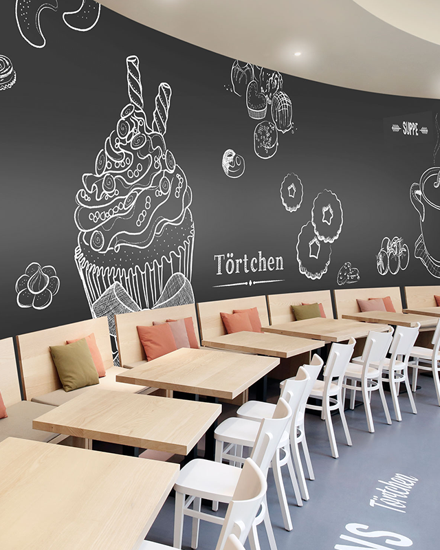 a-caf-with-abstract-wallpaper-for-commercial-spaces-featuring-chalk-style-dessert-drawings-on-a-black-background-wooden-tables-white-chairs-and-cushioned-benches A café with Abstract Wallpaper for Commercial Spaces, featuring chalk-style dessert drawings on a black background, wooden tables, white chairs, and cushioned benches