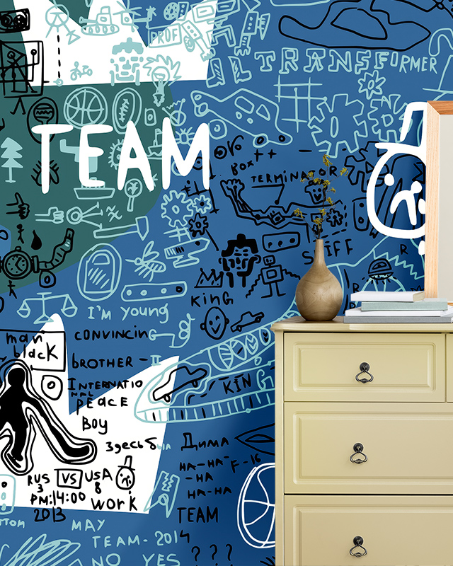 a-colorful-doodle-filled-sports-wallpaper-trends-mural-with-team-text-is-paired-with-a-light-yellow-dresser A colorful, doodle-filled sports wallpaper trends mural with "TEAM" text is paired with a light yellow dresser.