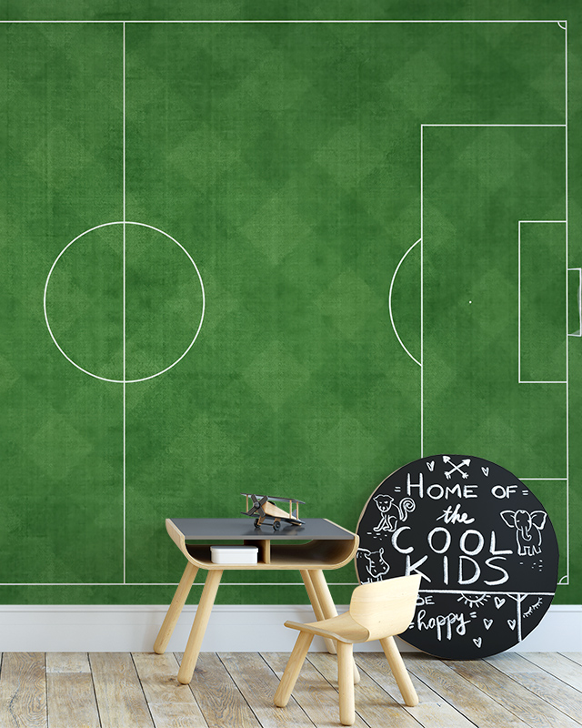 A game room with a green soccer field design, featuring sports wallpaper for game rooms, a wooden desk, chair, and chalkboard.