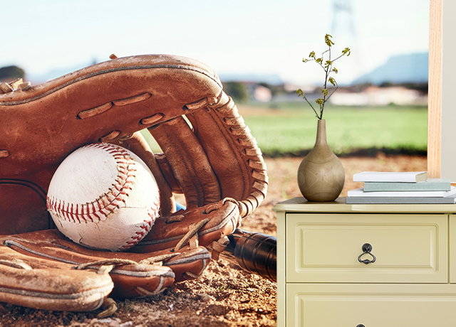 Baseball glove with ball mural behind a dresser showcasing different types of sports wallpapers for home decor.