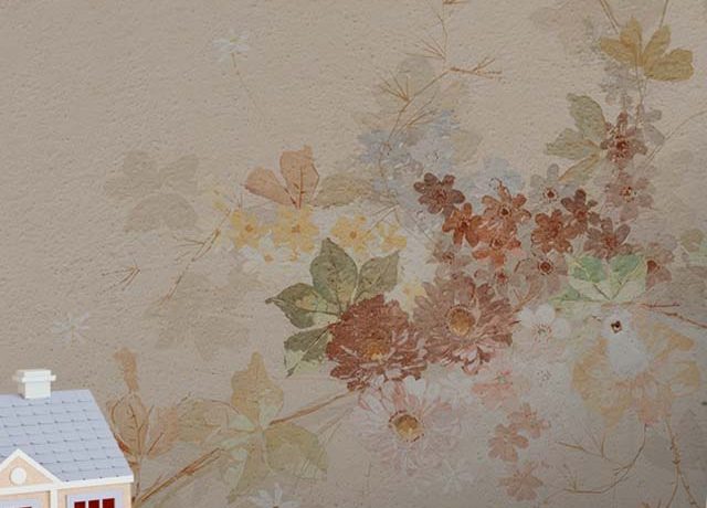 Beige wallpaper with delicate floral patterns, paired with a beige pouf and a small decorative house, showcasing Beige Wallpaper Color Pairing.