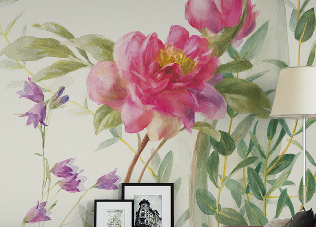 Pink and purple flowers on a light background create a serene look in front of a sofa and lamp, showcasing the Floral Wallpaper vs. Other Styles trend.