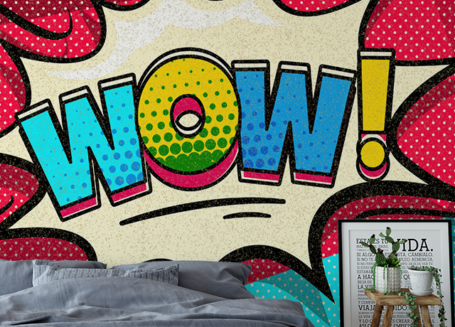 A bold "WOW!" comic-style mural with a bed, framed art, and plant in front. Pros and Cons of Removable Wallpaper.