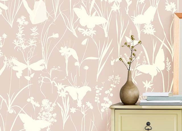 A floral beige wallpaper behind a green chest with a vase and books. Choosing the Right Shade of Beige wallpaper.