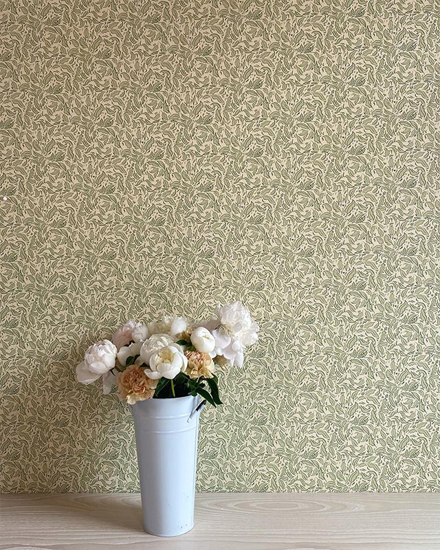 a-white-floral-arrangement-in-a-pale-blue-vase-against-green-william-morris-wallpaper-with-modern-art-influences A white floral arrangement in a pale blue vase against green William Morris wallpaper with modern art influences.