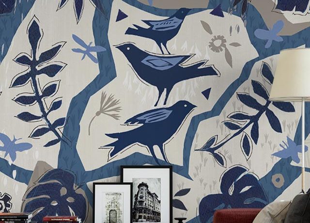 Colorful bird-themed wallpaper in a living room with framed art and books, showcasing installing peel and stick wallpaper.