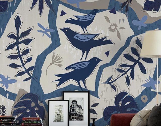 Colorful bird-themed wallpaper in a living room with framed art and books, showcasing installing peel and stick wallpaper.