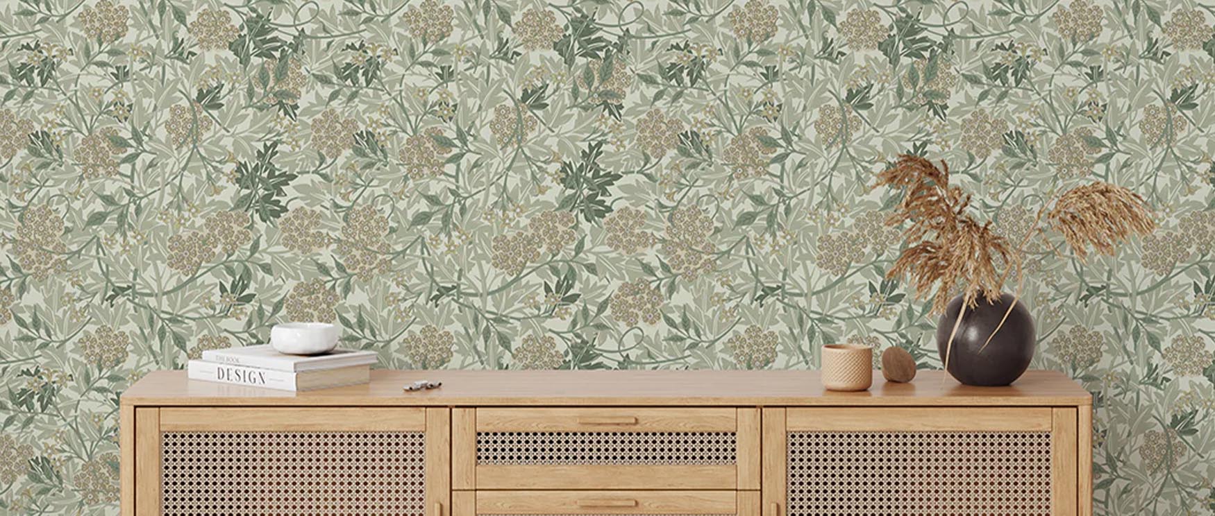Floral William Morris wallpaper with modern art behind a wooden console table, decorative vase, and dried plants.