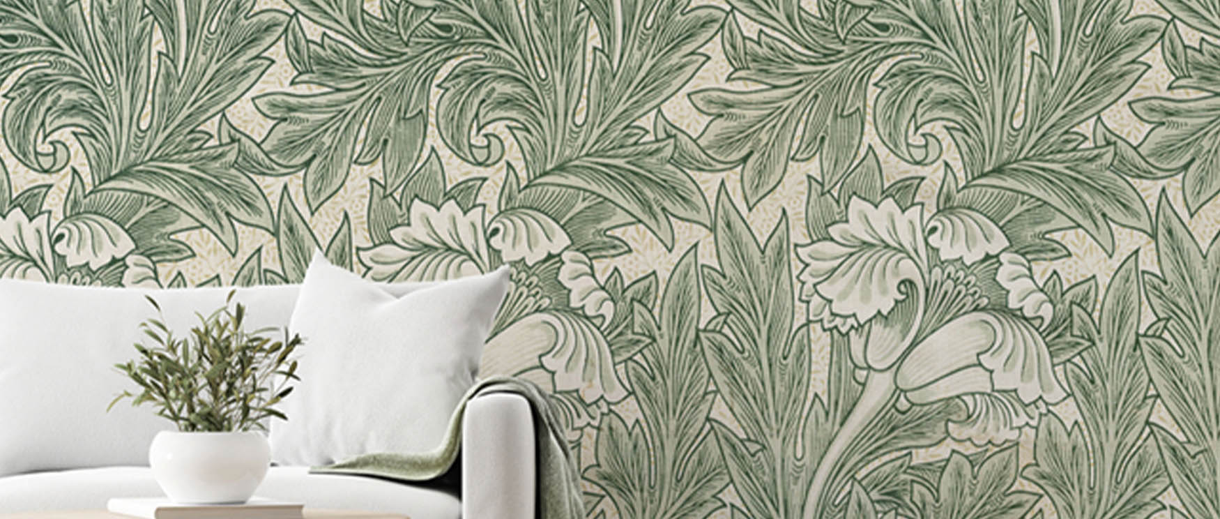 Green William Morris wallpaper with floral patterns, white couch, white pillow, and potted plant on a side table.