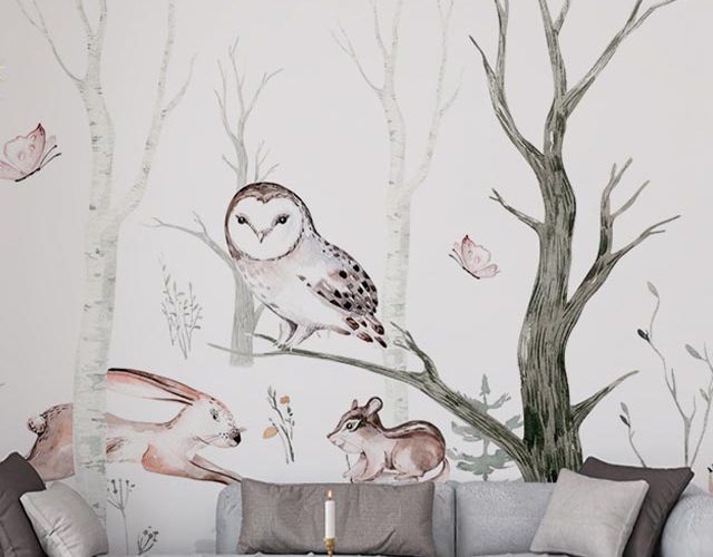 Illustration of an owl, rabbit, and mouse in a forest scene, with a gray sofa and coffee table in front, featuring removal of peel and stick wallpaper.