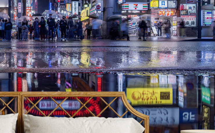 Japandi wallpaper with warm tones and cool tones depicting a rainy Tokyo street scene, behind a cozy bed setup.