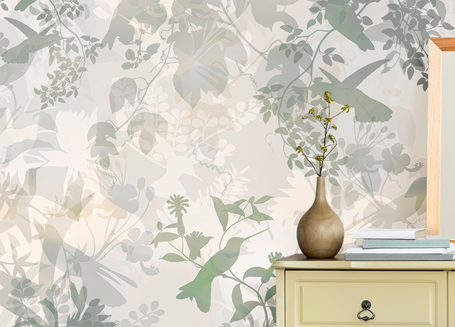 Leaf-patterned Removable Wallpaper vs. Traditional Wallpaper behind a beige dresser with a vase and stacked books.