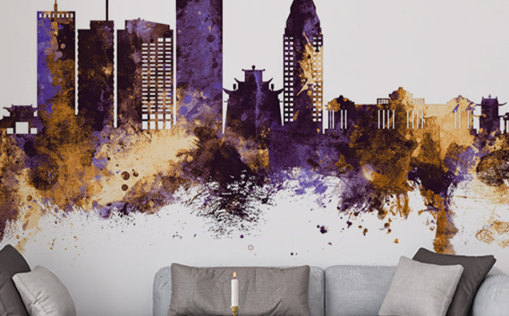 Modern office wallpaper designs featuring an abstract city skyline in purple and gold tones behind a grey sofa.