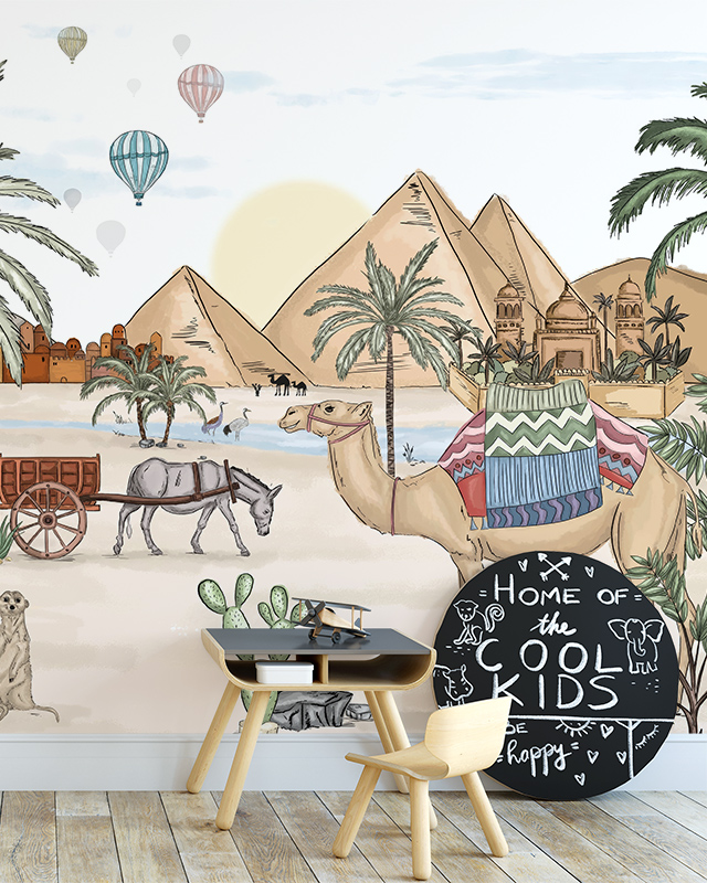 Nursery with a children's table, chair, and chalkboard in front of Beige Wallpaper for nursery featuring pyramids, camels, palm trees, and hot air balloons.