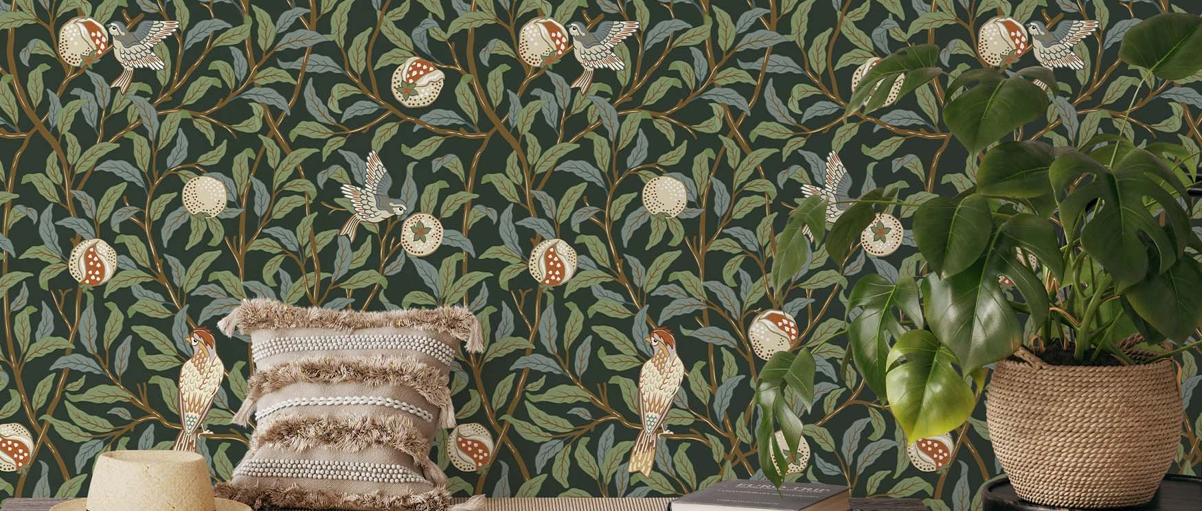 William Morris wallpaper in modern homes featuring birds and pomegranates, with a woven pillow, plant, and books in front.