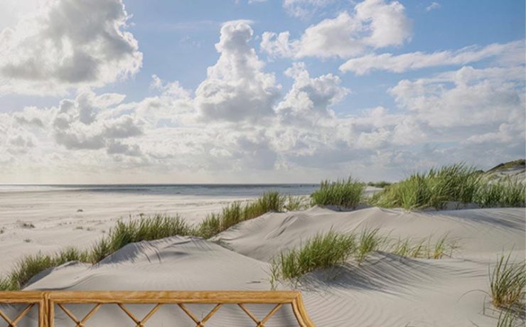 Bedroom with coastal-themed bright wallpaper for small spaces, featuring sand dunes and a blue sky with clouds.