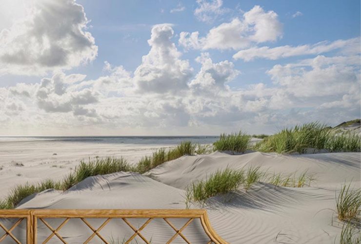 Bedroom with coastal-themed bright wallpaper for small spaces, featuring sand dunes and a blue sky with clouds.