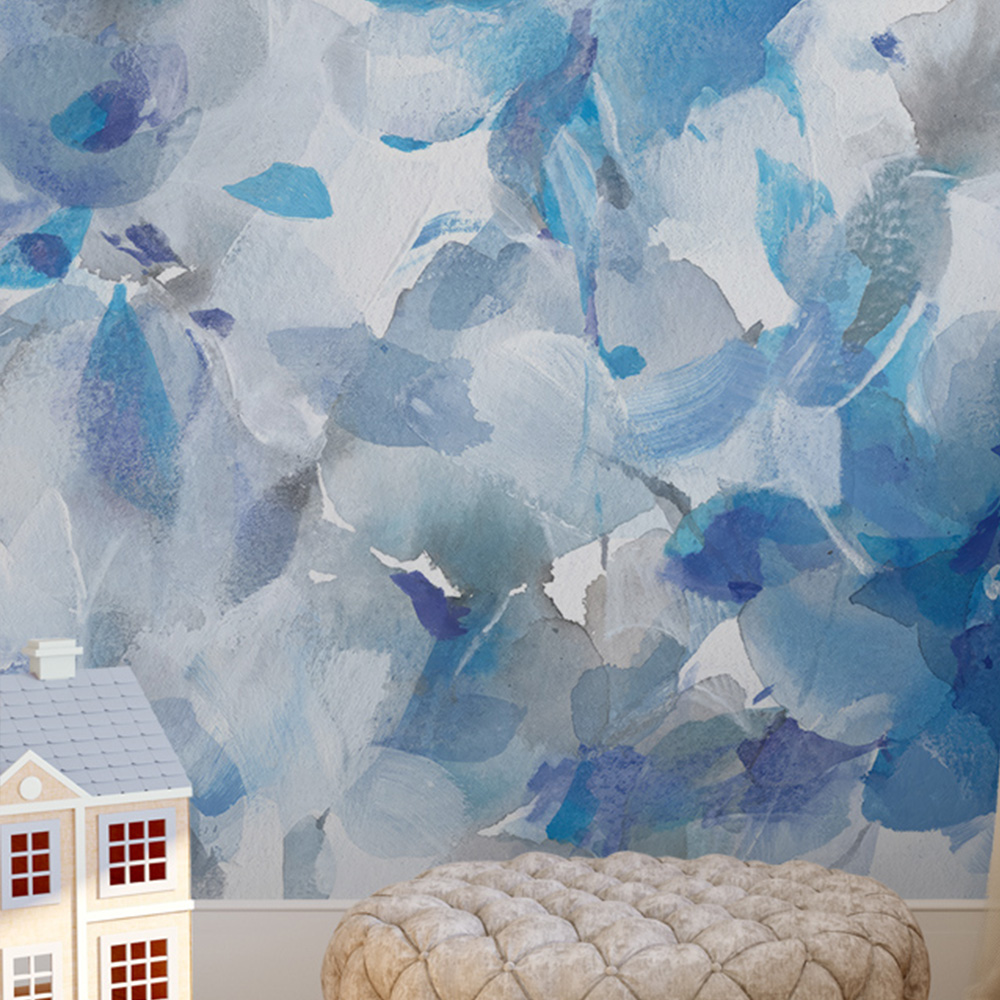  Abstract floral blue wallpaper with watercolor-like patterns behind a cream-colored pouf and toy house in a cozy room 