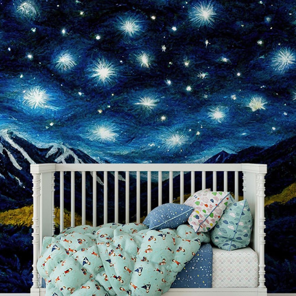  Starry night-themed blue navy wallpaper with glowing stars and mountain silhouettes behind a crib. 