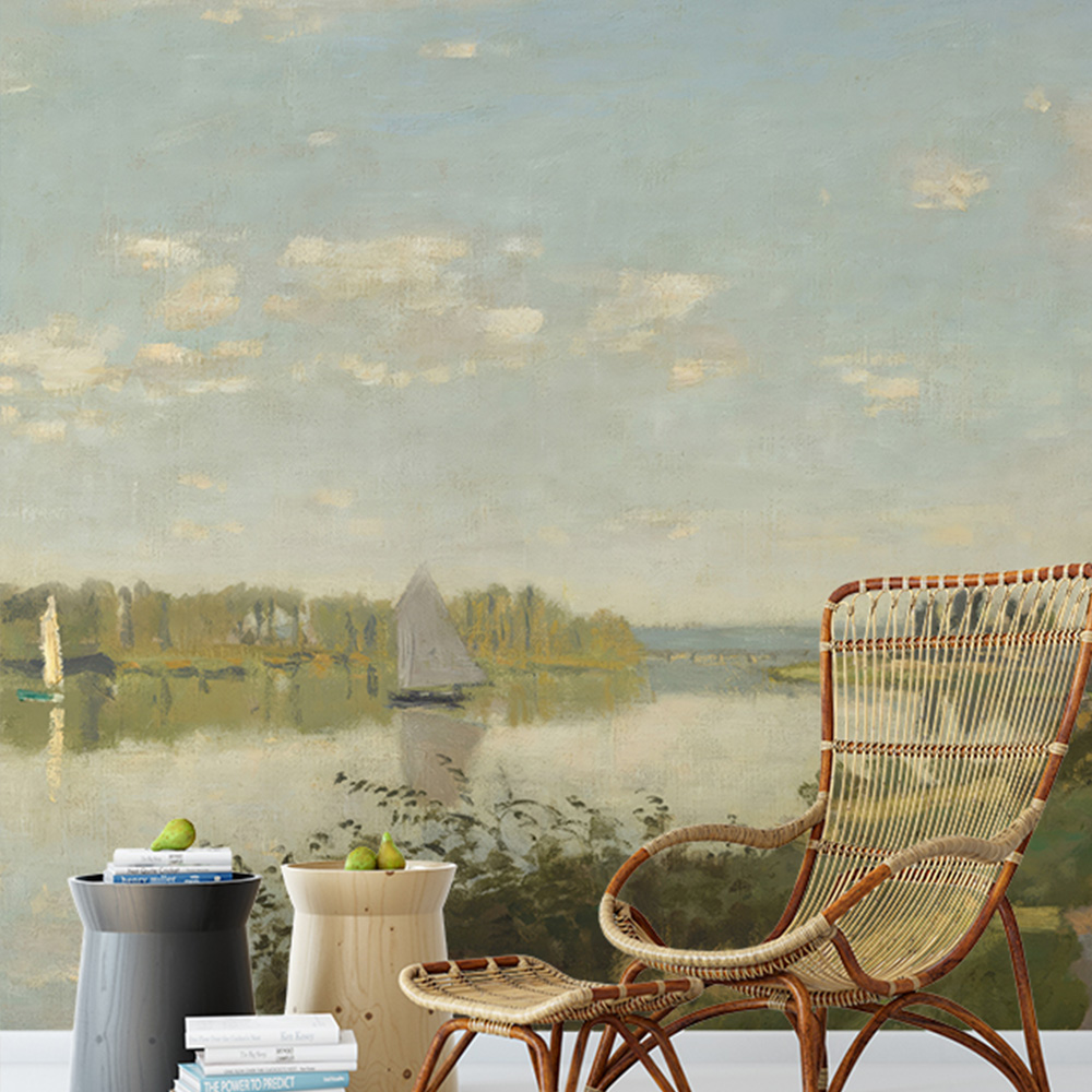 lake scene with a sailboat on a vintage blue wallpaper behind a wicker chair and side tables in a living space 